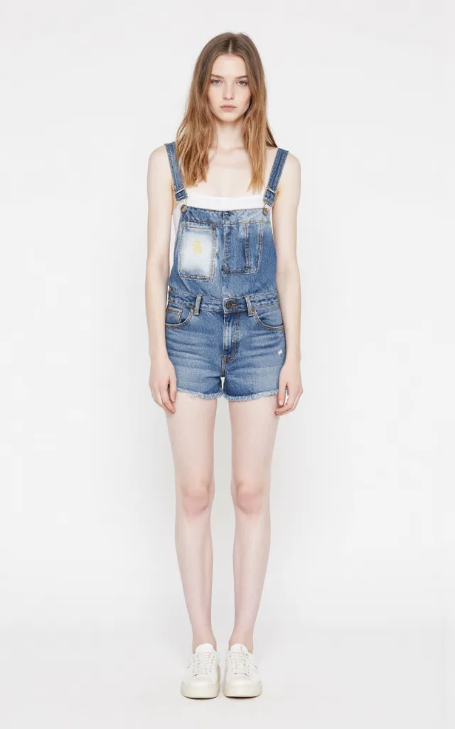 A French female model wearing Tomboy   style clothing, against a white background, in a front   facing shot focusing on shoes